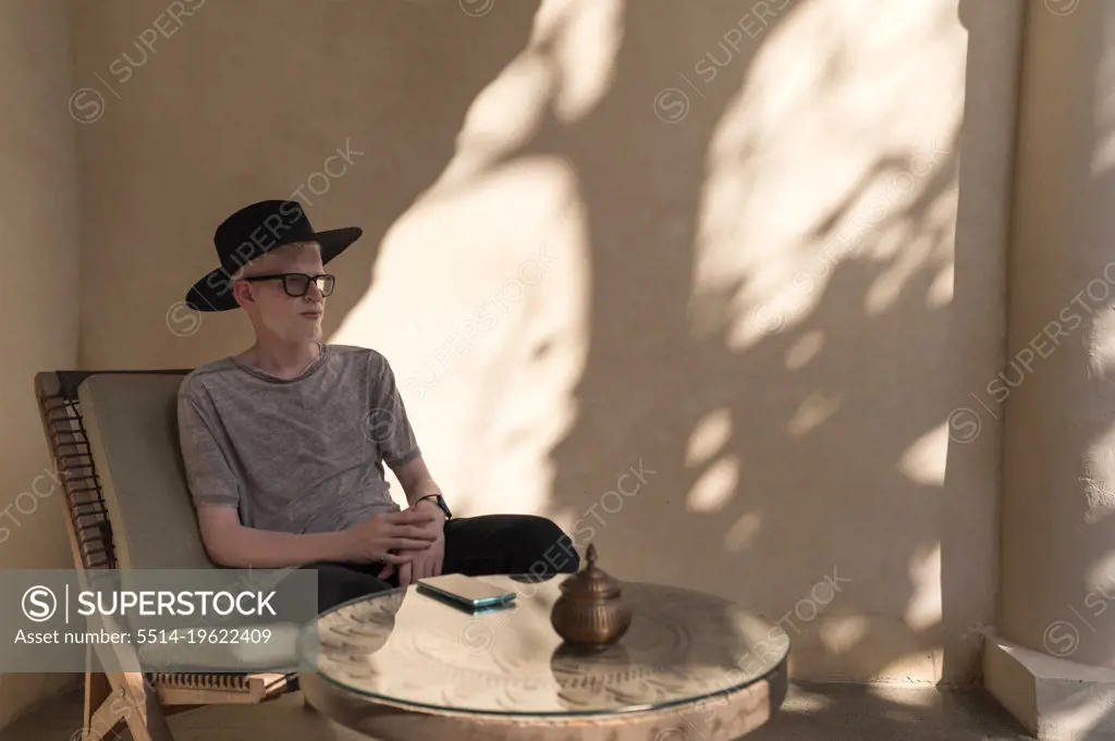 Albino man sitting at the outdoor cafe looking away