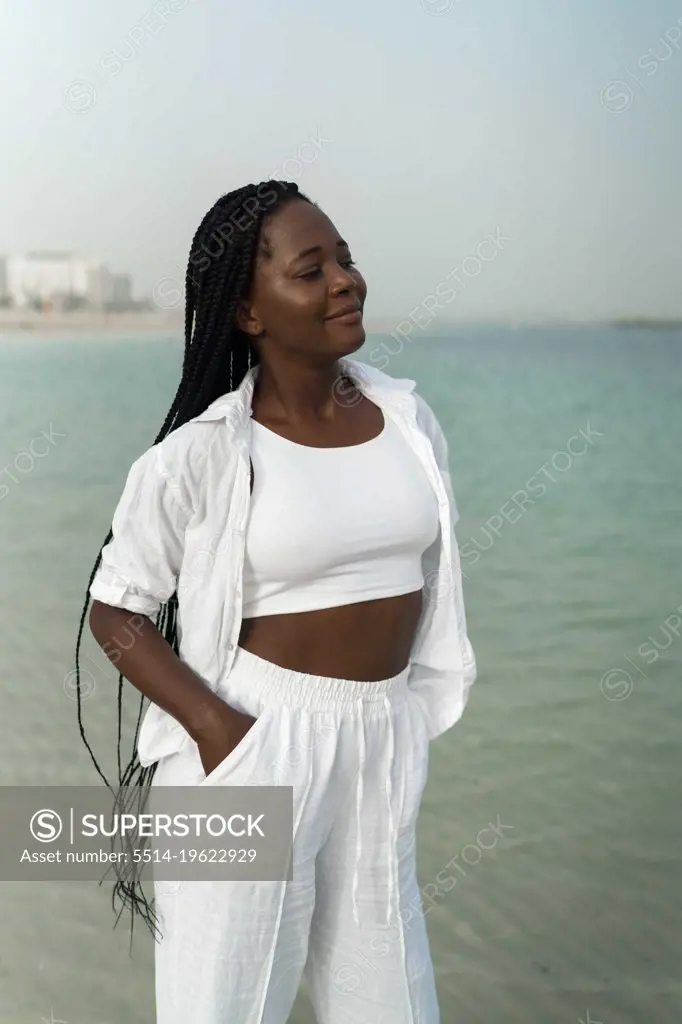 Woman with braids standing at the beach wearing white outfit