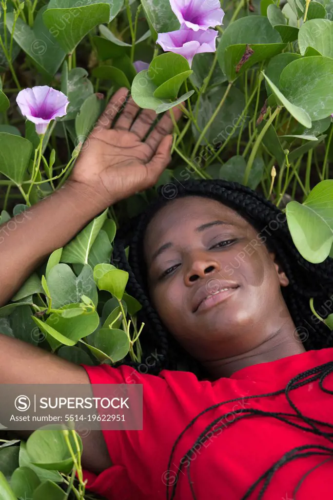 Woman with braids laying down between green and purple plants