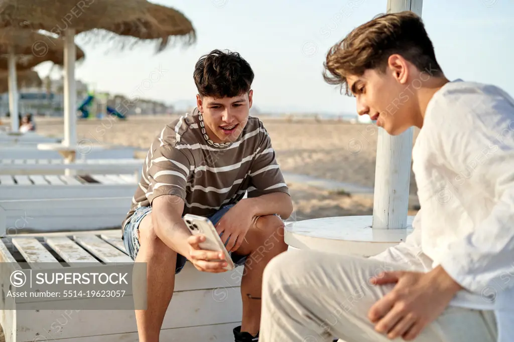 gay couple outdoors having fun and using looking at mobile.
