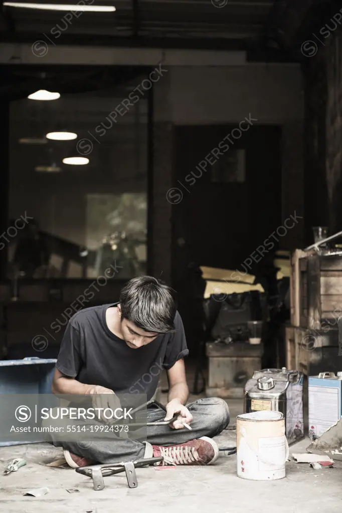 mechanic working on motorcycle part at custom bike shop in Bangkok