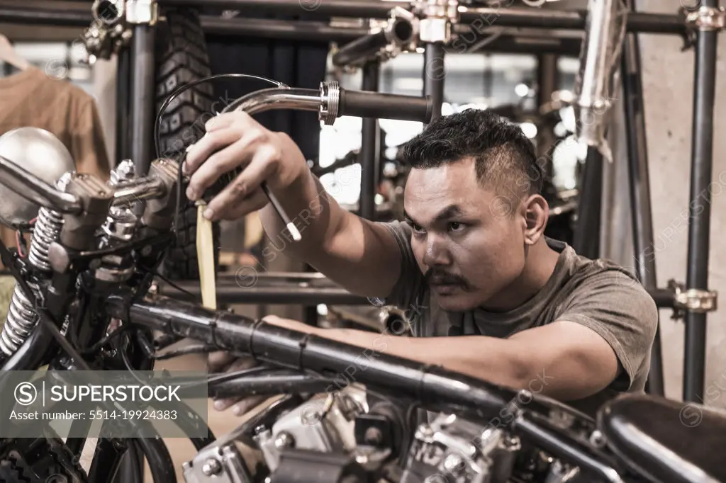 mechanic working measure up motorcycle at custom bike shop in Bangkok
