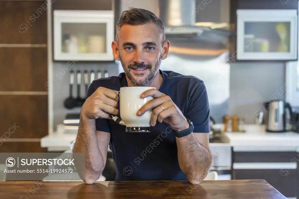 A handsome man drinking a coffee while looking at camera