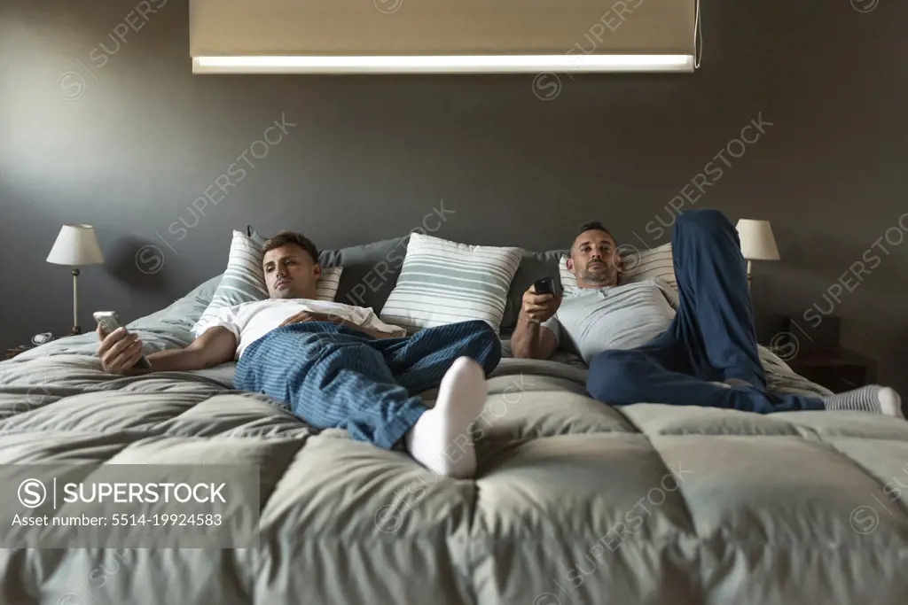 Gay male couple relaxing in bed.