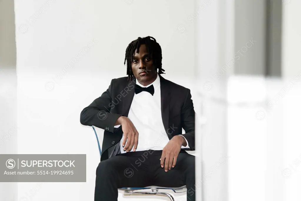 Portrait of the black man with dreadlocks wearing a suit sittin