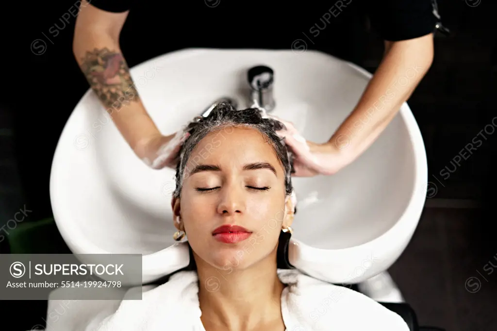 Hairstylist Washing Hair Of Female Customer