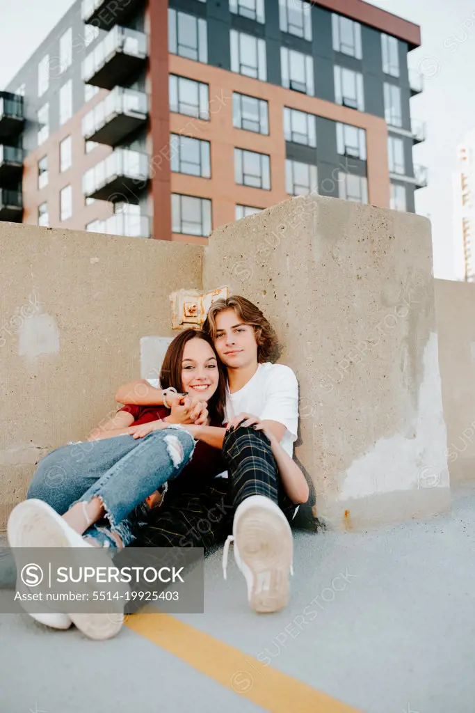 teenage boyfriend and girlfriend embracing on a garage rooftop