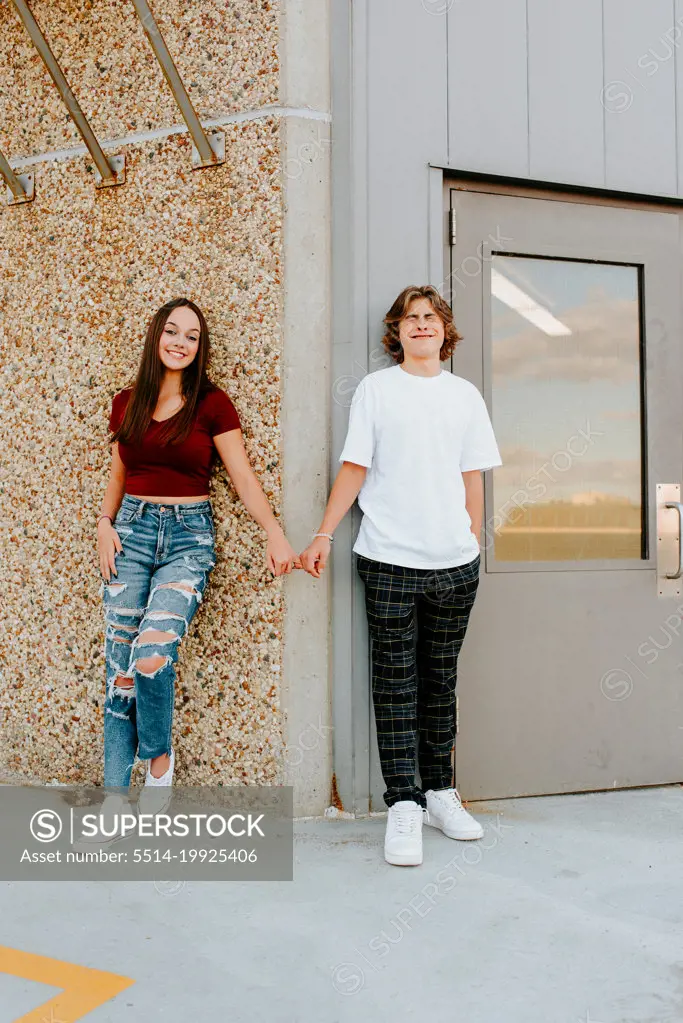 teen boy being silly holding pinkies with girlfriend on garage rooftop