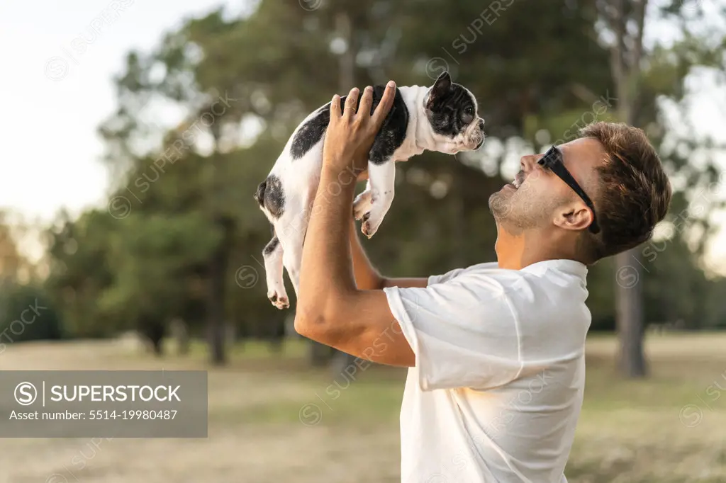 Handsome young man holding up a french bulldog