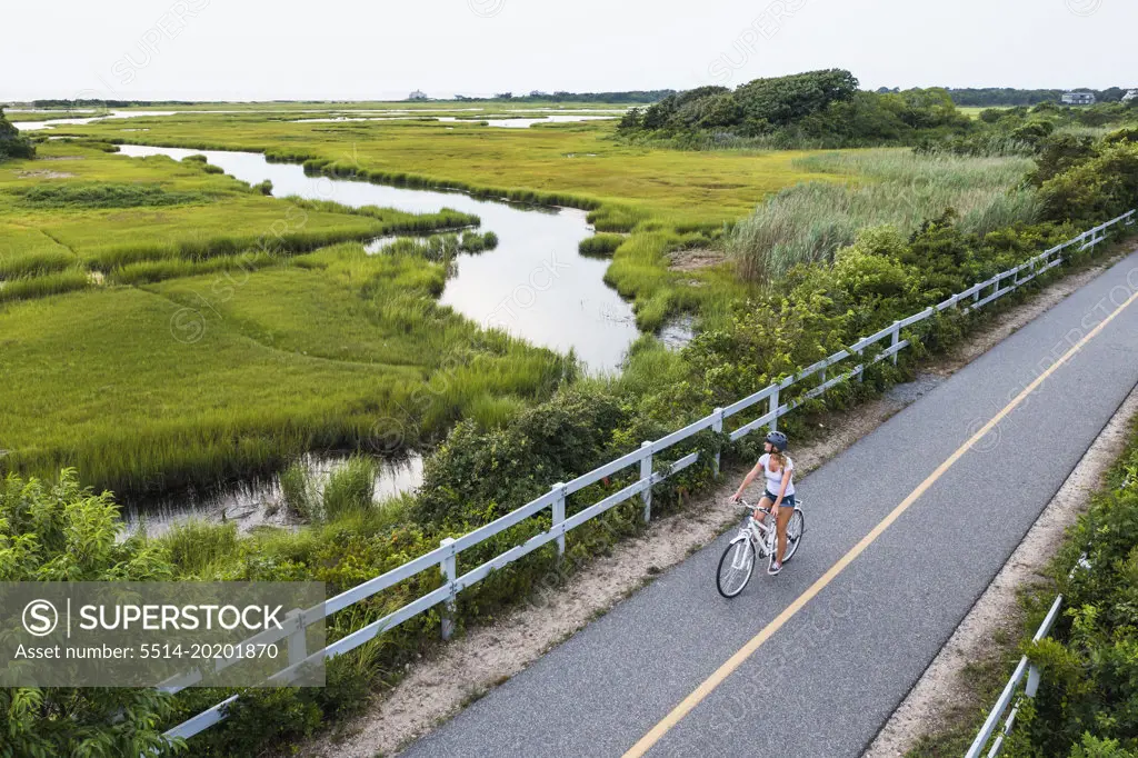 Aerial drone of Woman biking through Cape Cod Marshes bike path