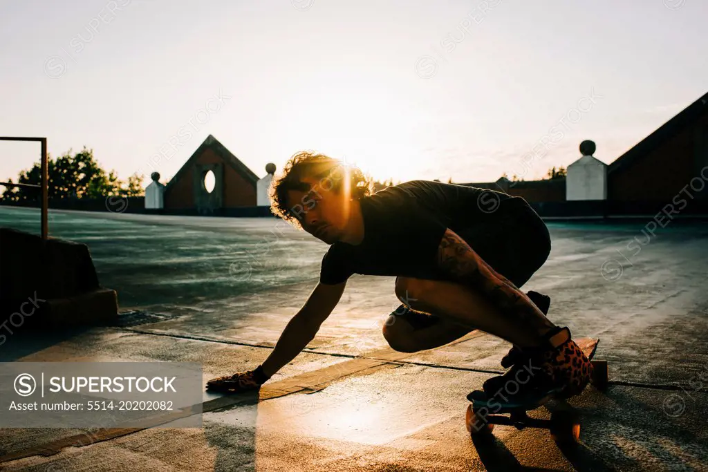man long boarding on the top of a building at sunset
