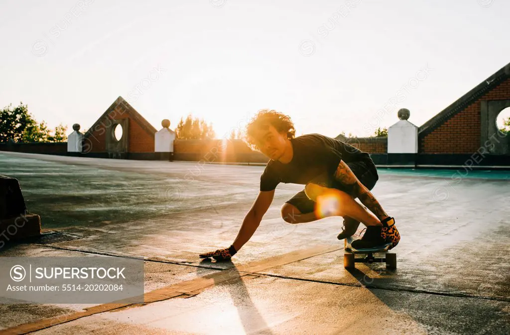 portrait of a man skateboarding in a car park at sunset