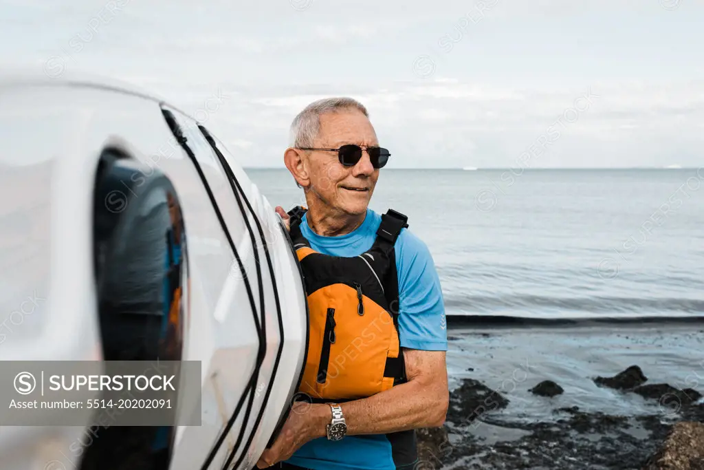retired man exercising kayaking at the beach on a sunny day