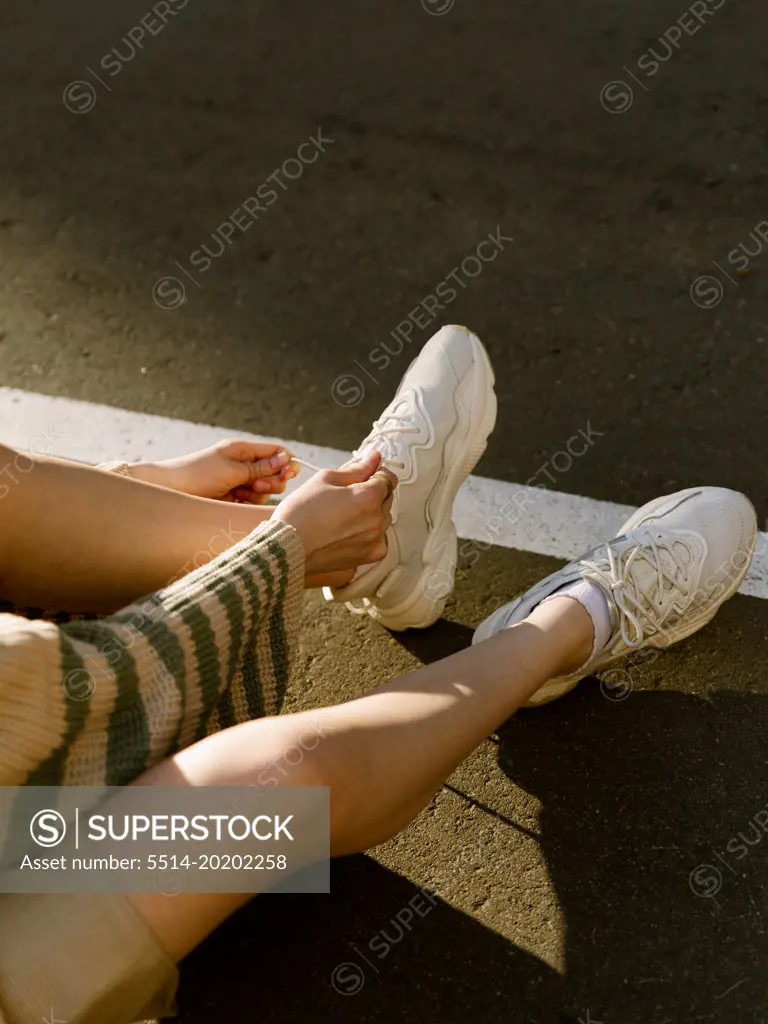 Girl tying shoelaces. In parking