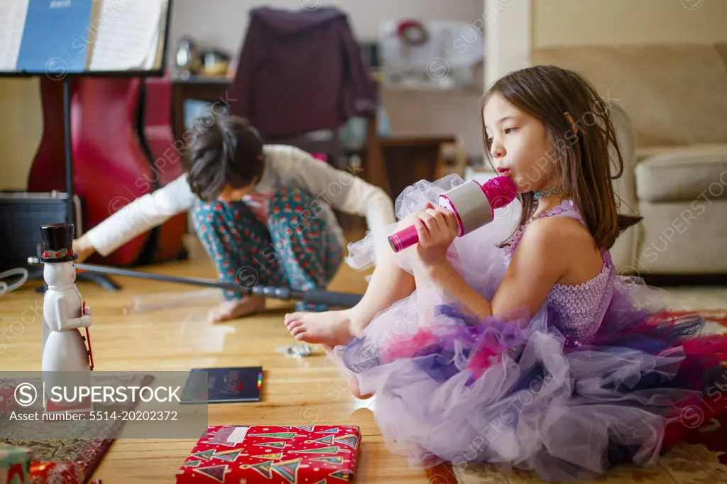 Little girl in costume and brother play with Christmas gifts