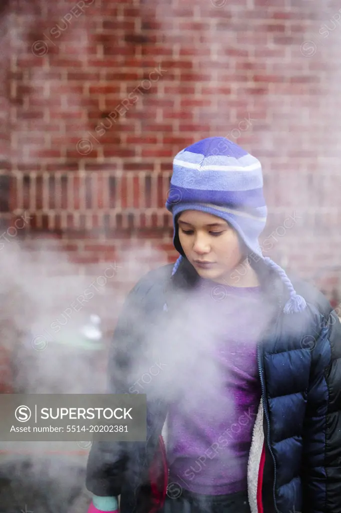 A beautiful serious child standing in smoke gazes down
