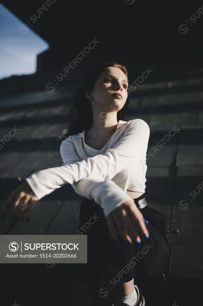urban lonely girl sitting under a dark bridge