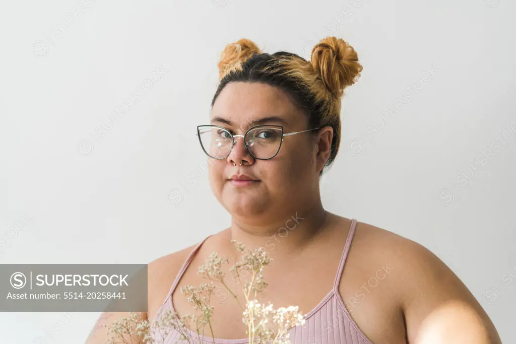 Plus sized woman portrait holding flowers looking at camera
