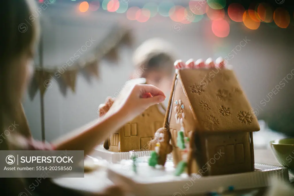 Siblings decorate gingerbread houses with candy at Christmas