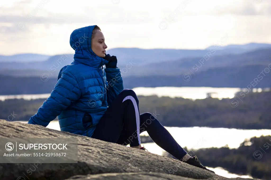 A woman in a blue jacket  overlooking a lake