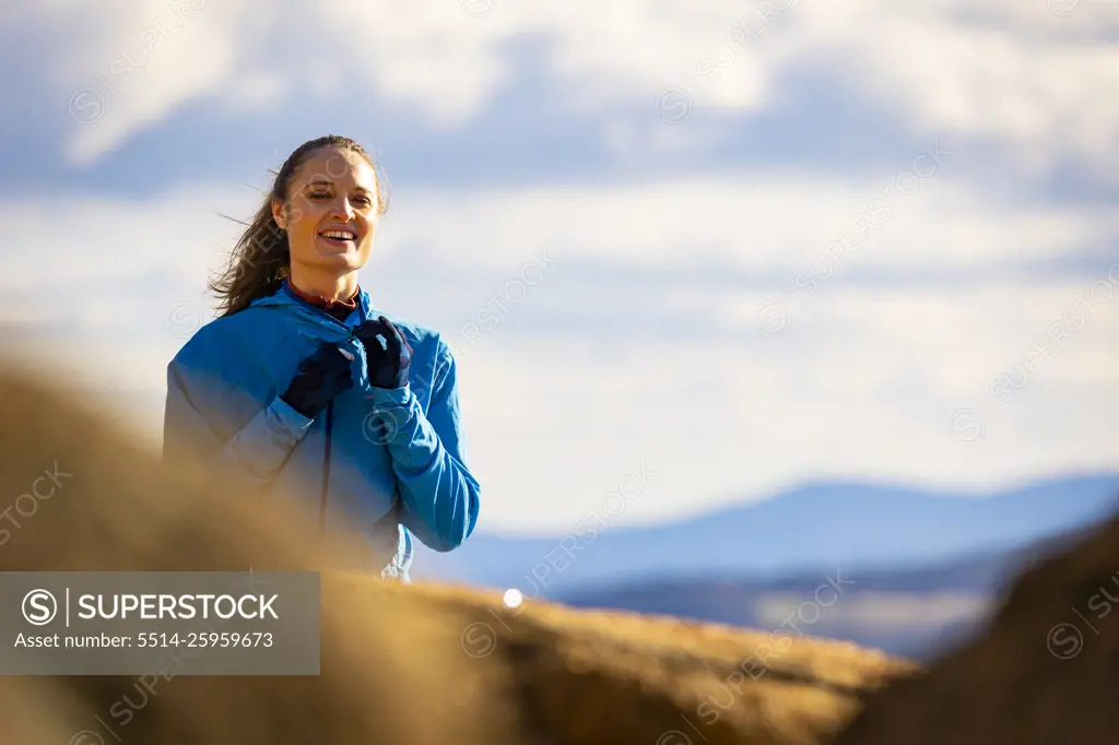 A woman in a blue jacket smiling in the mountains