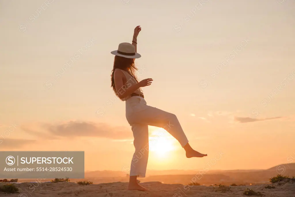 young girl on vacation dances in the sunset