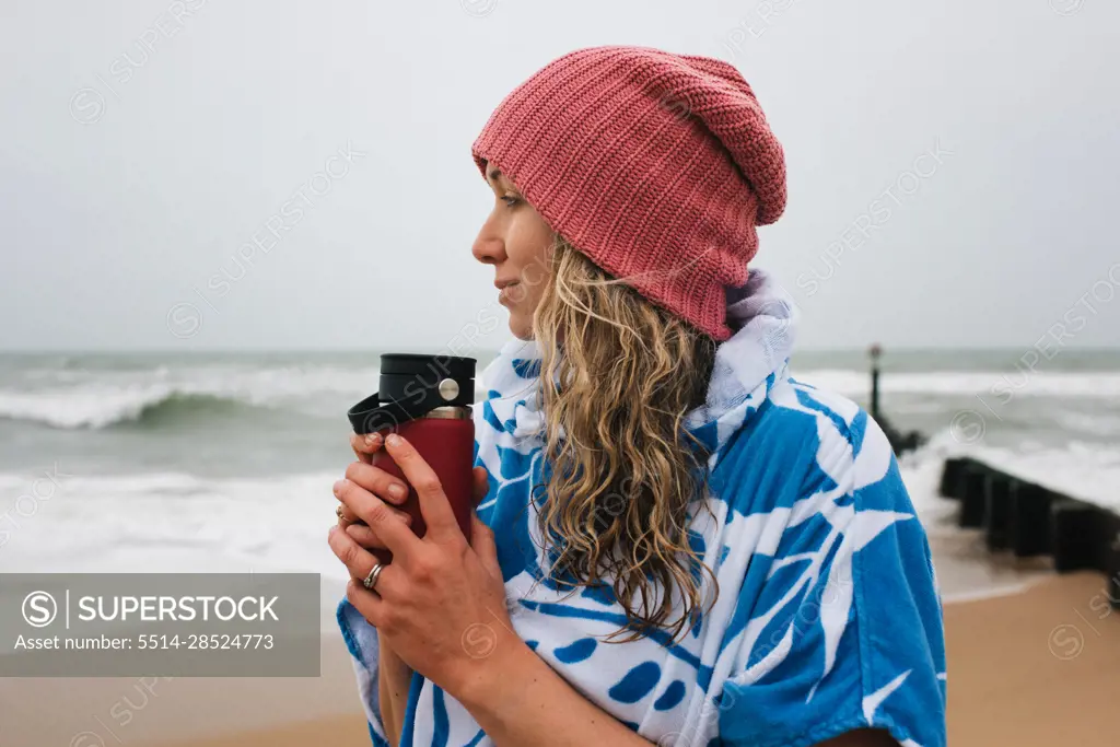 Woman holding a warm drink after cold water swimming in the sea