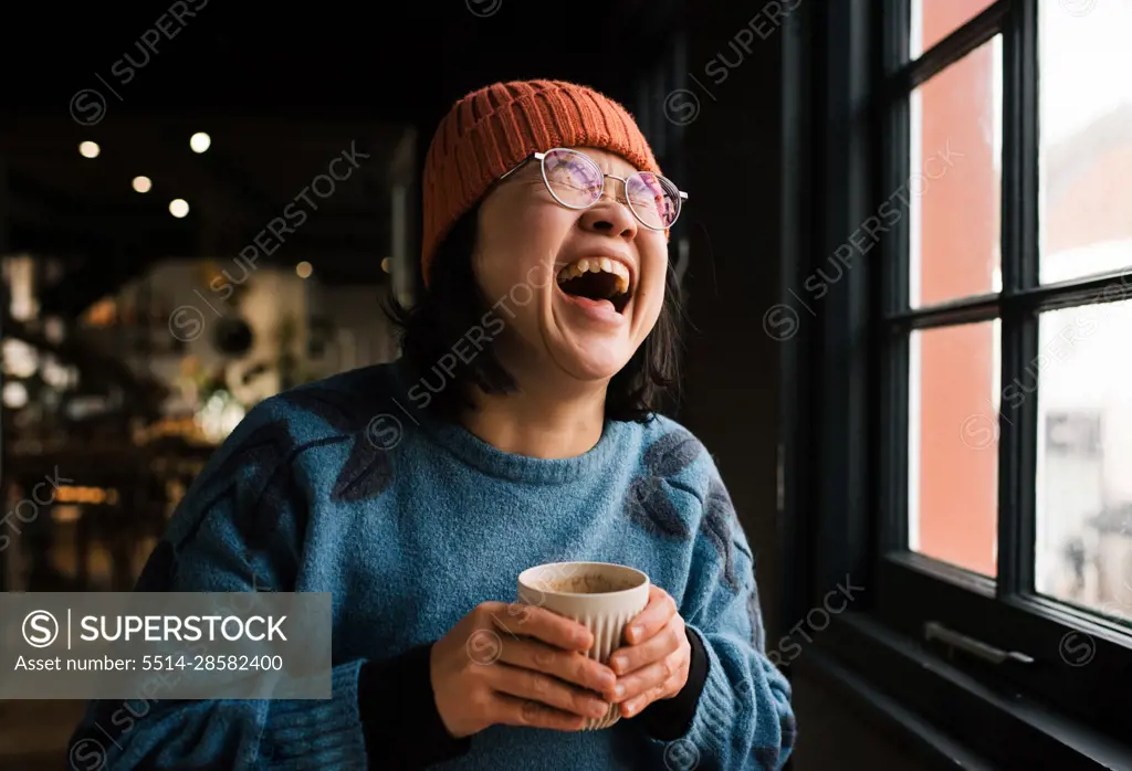 Asian woman laughing having coffee in a cafe