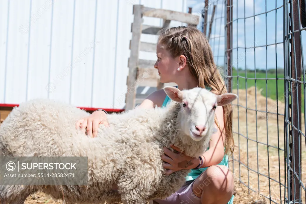 Blond tween girl with a white lamb.