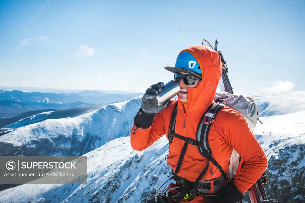 Ski mountaineer taking a break and drinking a hot beverage