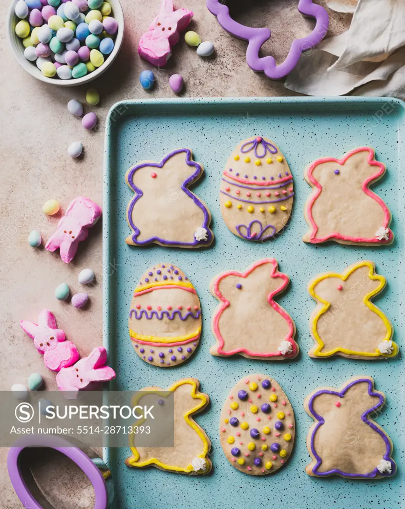 Easter cookies shaped like eggs and bunnies on green tray from above.