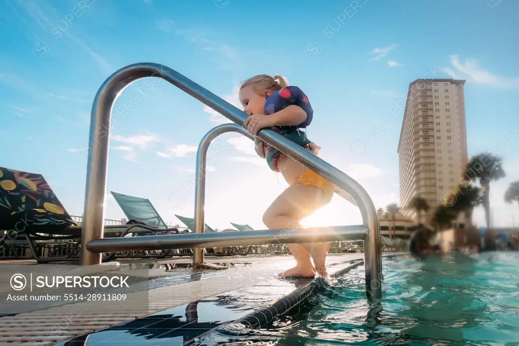 Young girl getting out of pool at tropical beach family resort