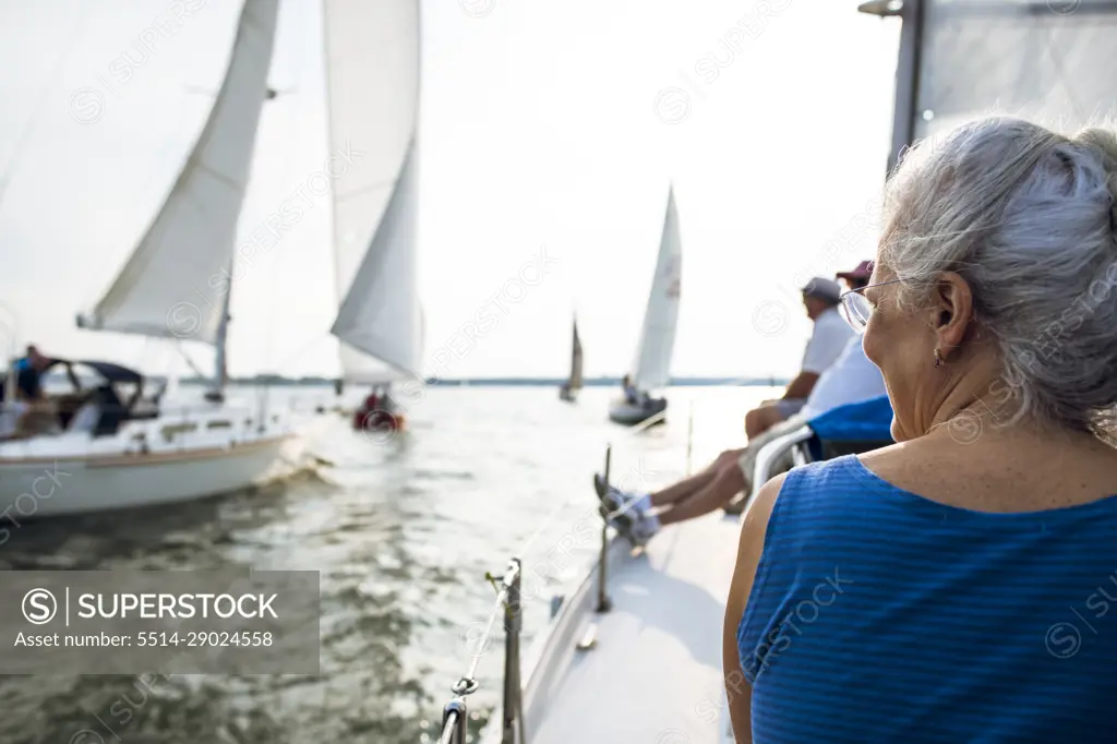 Middle aged Woman enjoying summer sail race during golden hour