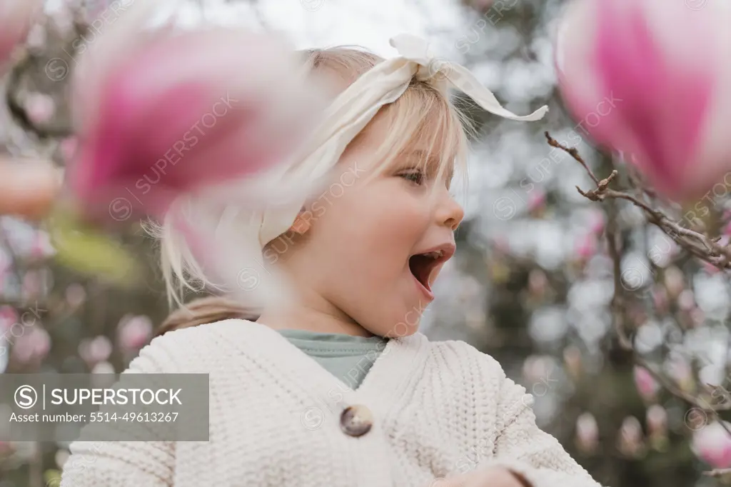 Cute little blonde girl in magnolia flowers