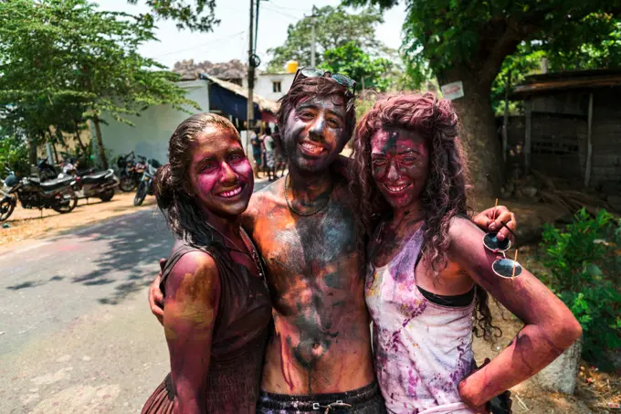 Hampi, India - April 07, 2019: happy young tourists painted in colorful pigments celebrating Holy Festival in rural village in Hanuman Halli, Karnataka, India