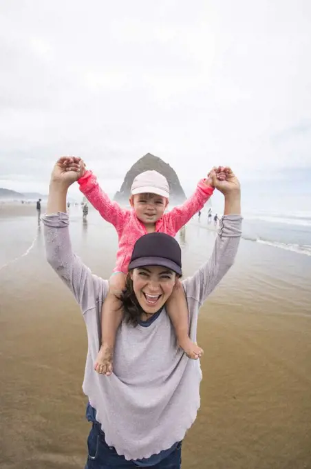 Happy mom gives daughter shoulder ride at Cannon Beach.