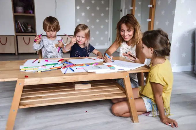 Mom with young children drawing with felt-tip pens