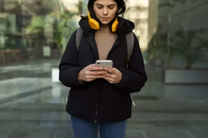 young woman listening music using yellow headphones