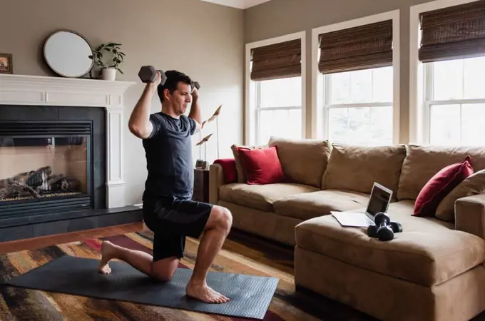 Man working out with weights at home using online exercise program.
