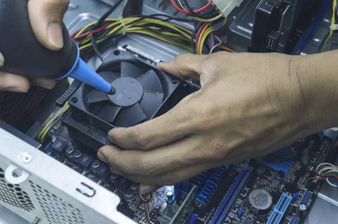 Men hands of Computer technician Cleaning the CPU fan of the computer.