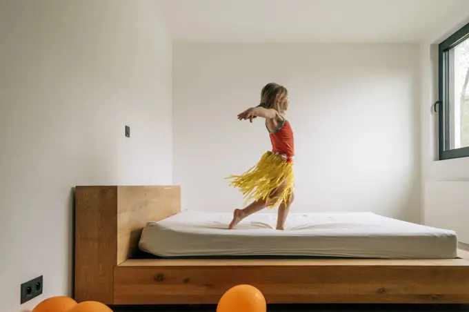 little girl playing as hawaiian dancer on parents bedroom