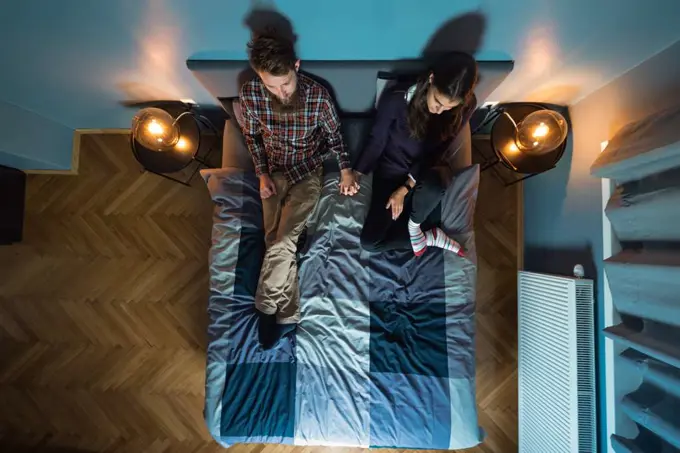Image from above of young couple watching tv on the bed together