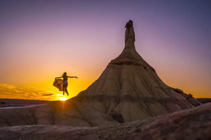 Silhouette of a blonde girl in a long dress in the Bardenas. Spain