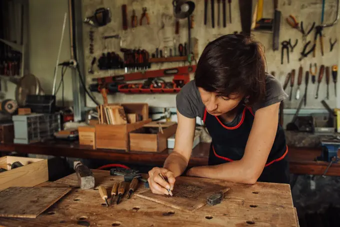 Female woodworker working at the workbench in a workshop