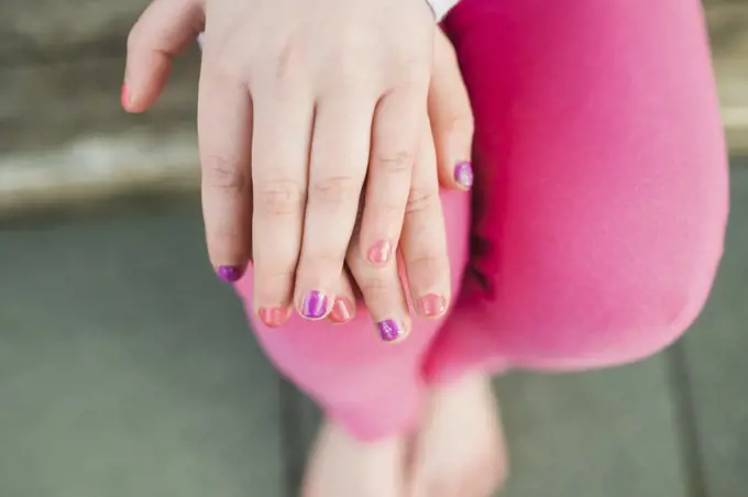 Overhead view of young girl showing painted nails