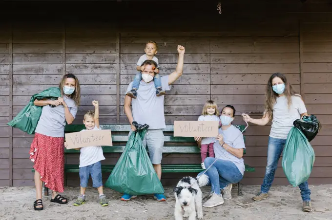 Group of volunteer families wearing medical masks and holding garbage