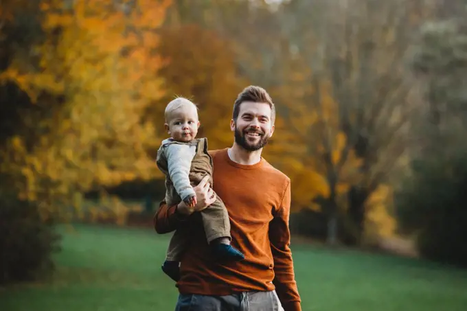 Father and son smiling at the park in a Fall day wearing earth tones