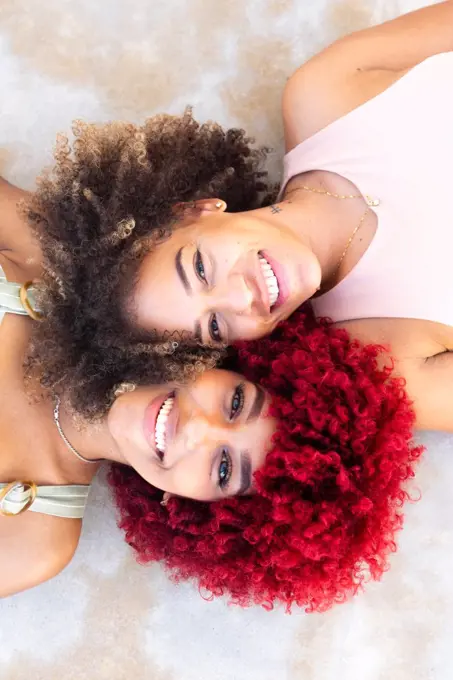Zenithal portrait of two latin women with afro hair on the ground.