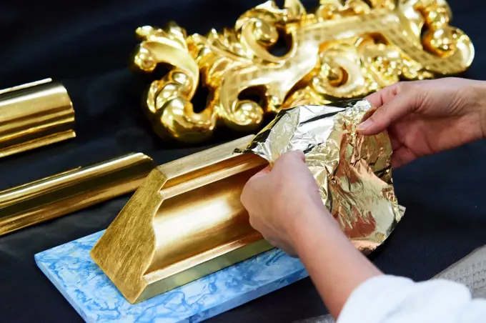 craftsman working to give gold to a piece of wood