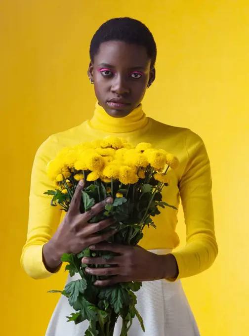 young fashionable black woman with bunch of yellow flowers isolated